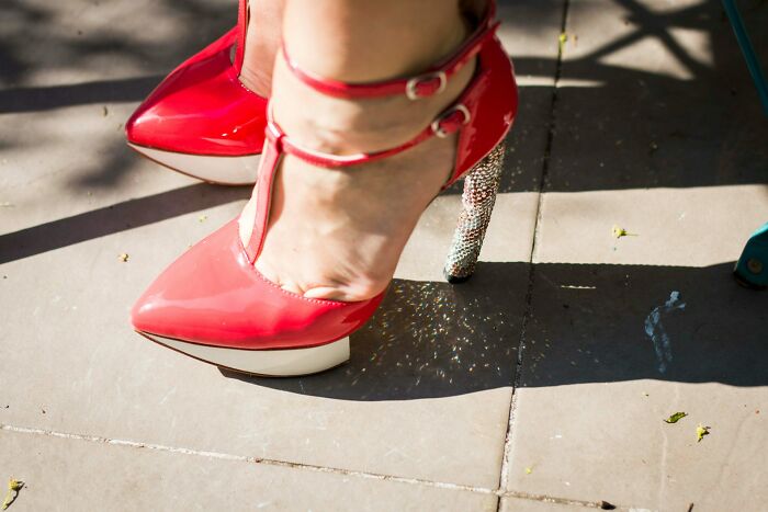 Red high heels with sparkling heels worn outdoors, representing high school controversies and unique education moments.