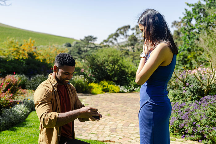 Man proposing to woman in garden, capturing a moment with an overwhelming feeling of needing to leave in outdoor setting.