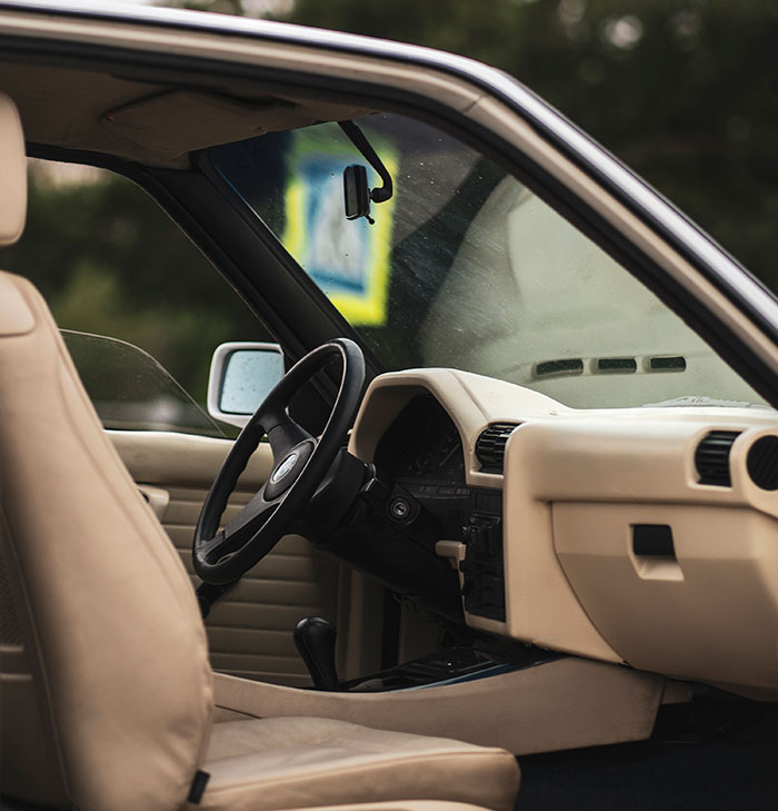 Interior view of beige car showing steering wheel and seats, illustrating situations when people got an overwhelming feeling to leave.