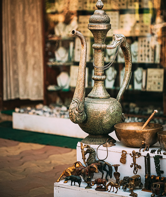 Antique brass pitcher and figurines displayed at a market capturing overwhelming feeling that they needed to leave moments.