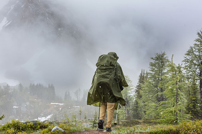 Person in raincoat hiking through misty forest, capturing the overwhelming feeling that they needed to leave the area.