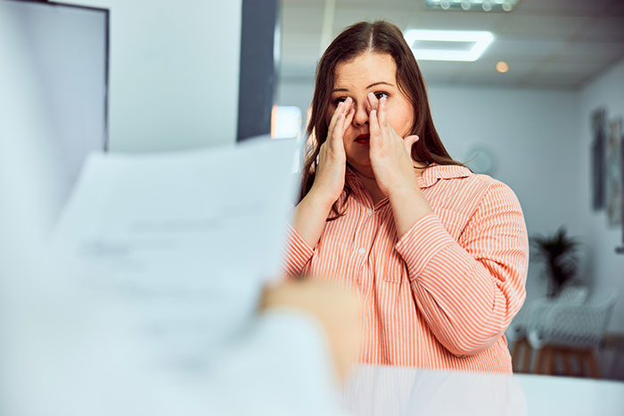 Woman in a striped shirt rubbing her eyes, showing an overwhelming feeling of needing to leave a tense situation.