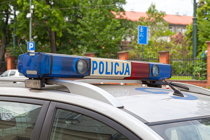 Police car with blue and red lights parked on a street near buildings, related to neighbor religious pamphlet police incident.