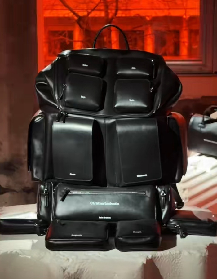 Black Christian Louboutin bag with multiple compartments displayed indoors under orange lighting. Black Christian Louboutin bag with multiple compartments displayed indoors under orange lighting.