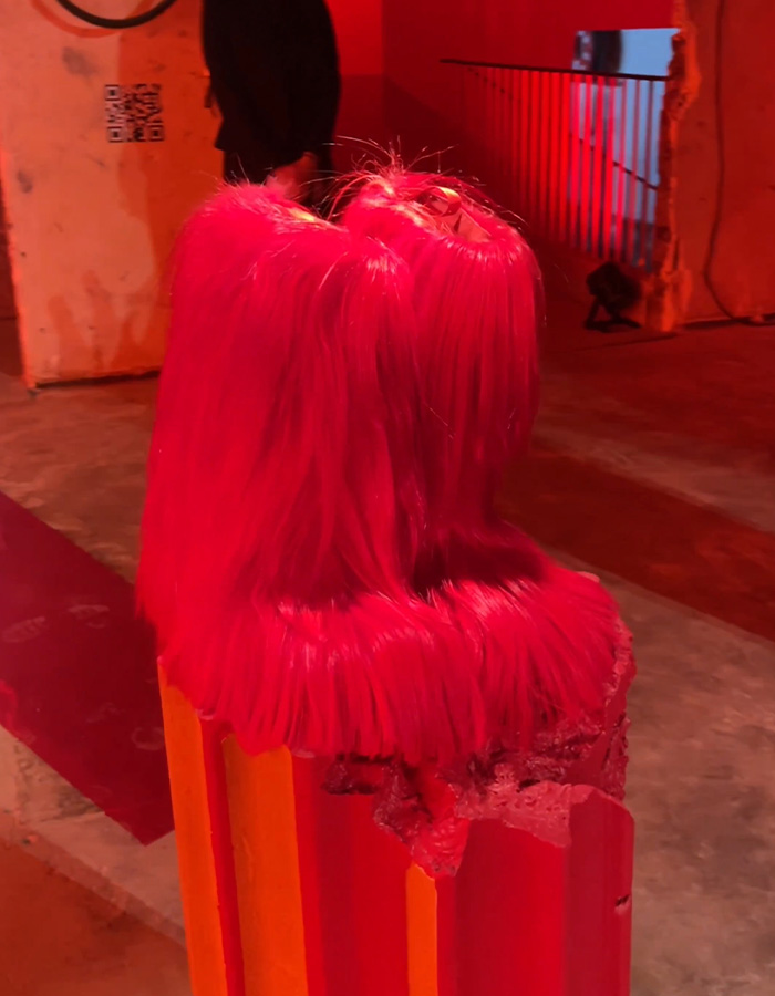 Three vibrant pink furry boots displayed on an orange and red platform at a fashion event for Christian Louboutin collection. Three vibrant pink furry boots displayed on an orange and red platform at a fashion event for Christian Louboutin collection.