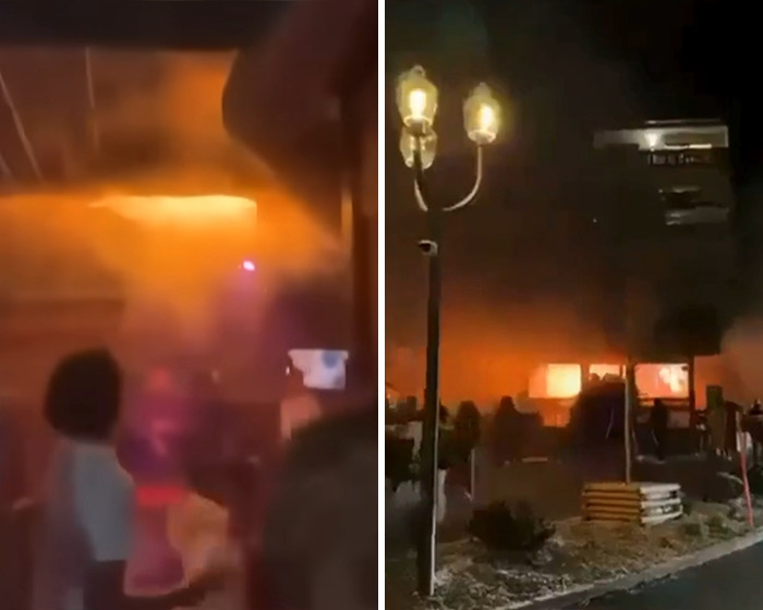 Orange flames and smoke engulf Swiss resort at night after horrific blaze, with people observing the scene from outside. Orange flames and smoke engulf Swiss resort at night after horrific blaze, with people observing the scene from outside.