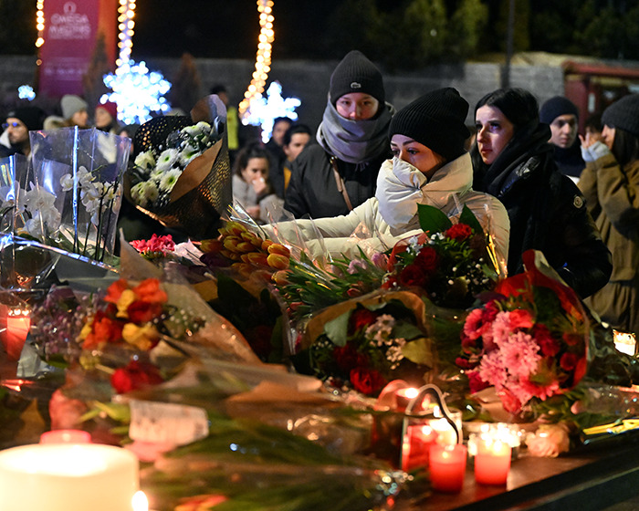 People wearing winter clothes lay flowers and light candles at a memorial for victims of the Swiss resort blaze tragedy. People wearing winter clothes lay flowers and light candles at a memorial for victims of the Swiss resort blaze tragedy.