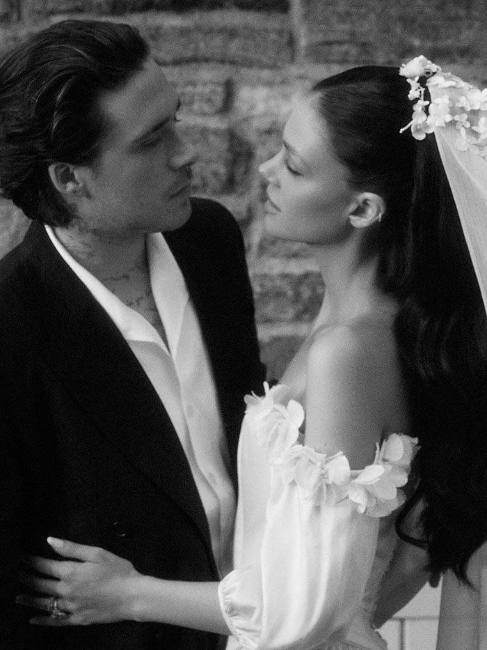 Nicola Peltz and Brooklyn Beckham in wedding attire, highlighting Nicola Peltz's tattoo with a pointed message to the Beckham family.