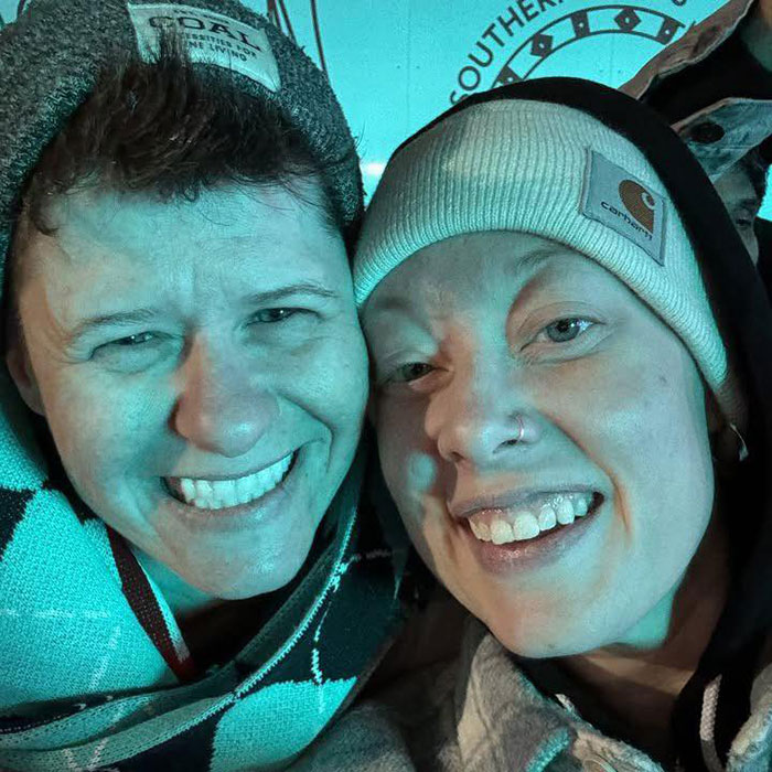 Father of ICE agent who slew Renee Nicole Good pictured with a smiling woman wearing winter hats in close-up.