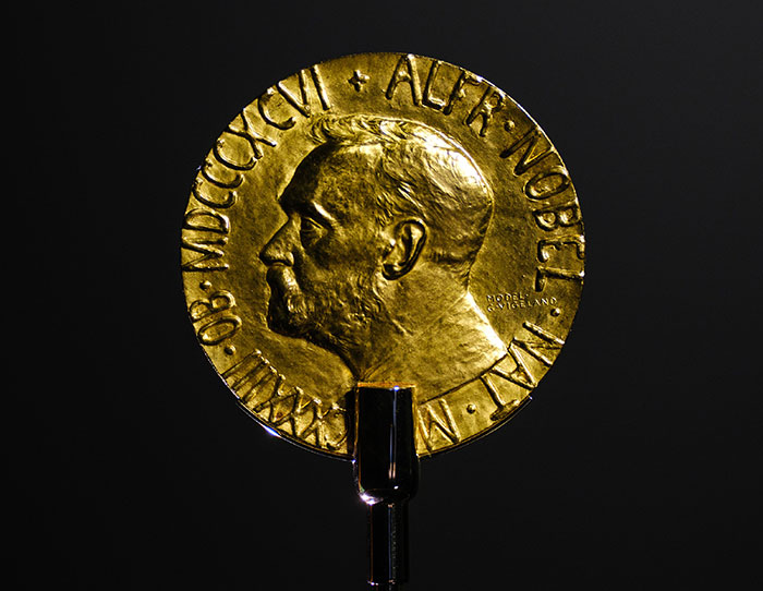 Close-up of a Nobel Peace Prize medal displayed against a dark background with intricate engravings.