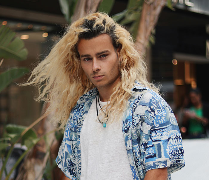 Young man with long blonde hair wearing a patterned shirt, illustrating the bald and divorced man shaming nephew story.