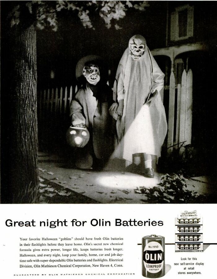 Vintage Halloween ad showing children in costumes using flashlights powered by Olin batteries at night.