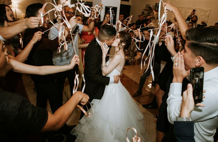 Couple kissing at wedding surrounded by guests celebrating with streamers, representing adult goals in life events.