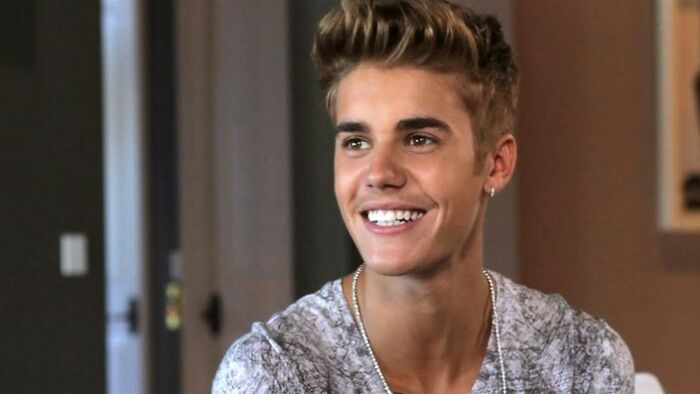 Young male celebrity smiling indoors, representing celebs who weren’t nepo babies and went from rags to riches.