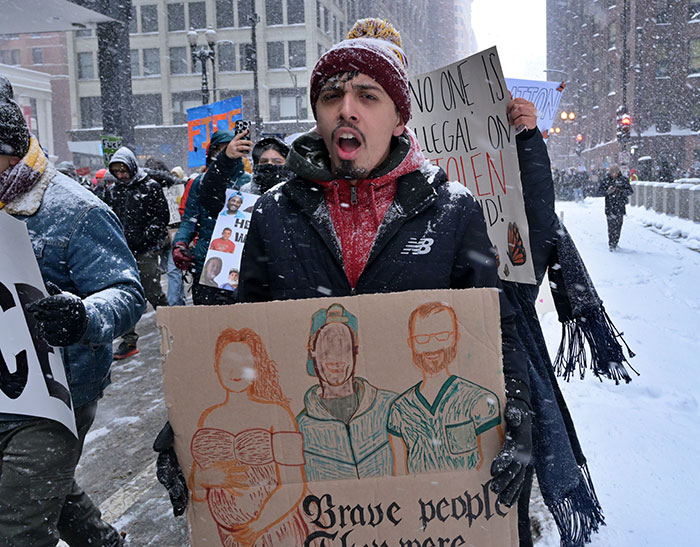 Protester in snowy street holding sign during heated debate on ICE immigration policies and SNL controversy. Protester in snowy street holding sign during heated debate on ICE immigration policies and SNL controversy.