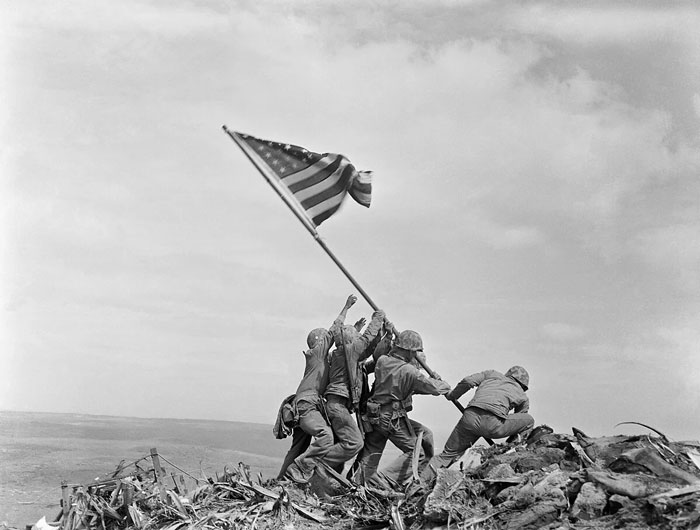 Soldiers raising an American flag on a battlefield, a powerful photo from countries that always stayed with me.