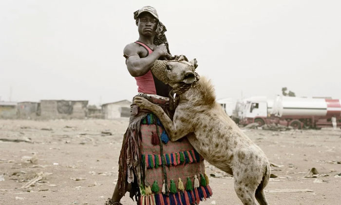 Man in traditional clothing standing with a hyena in a rural area, a powerful photo shared from their country that hits hard.