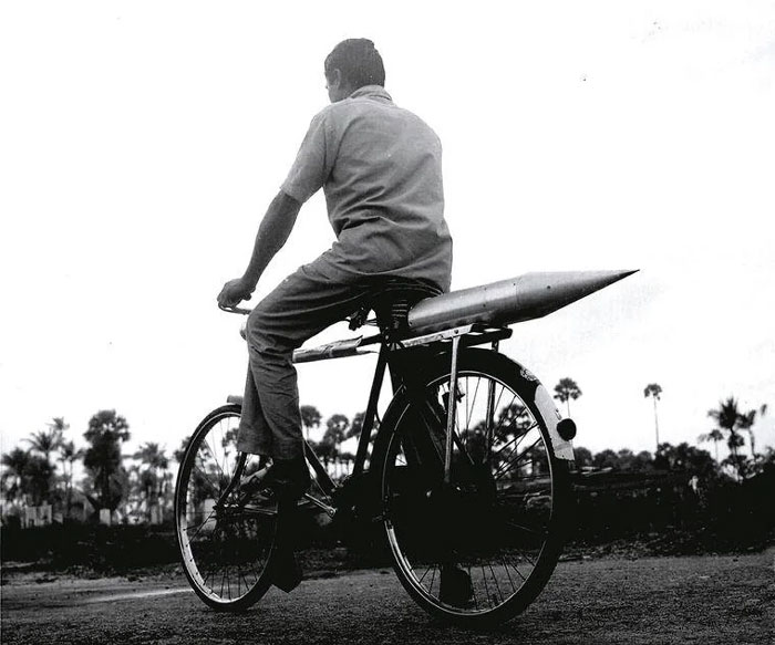 Man riding a bicycle carrying a missile in rural area, a powerful photo shared from a country that hits hard.
