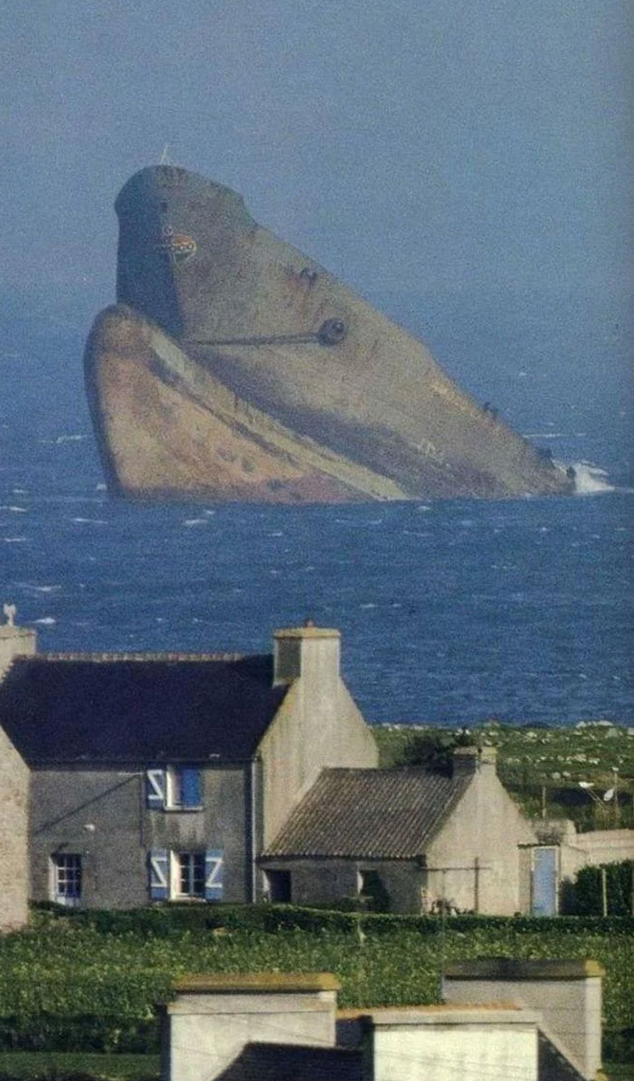 Rusty shipwreck off the coast near rural houses, a powerful photo shared from the country that always stayed with me.