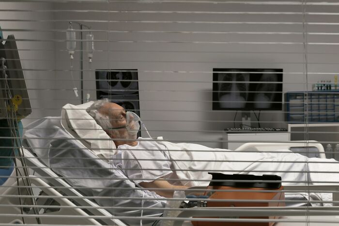 Elderly man in hospital bed with oxygen mask, medical equipment nearby, depicting a hidden story about people share wildest ways found out cheating.