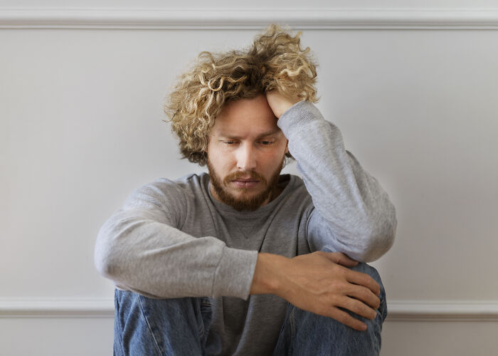 Young man with curly hair looking distressed and contemplative, reflecting on wildest ways people found out cheating.