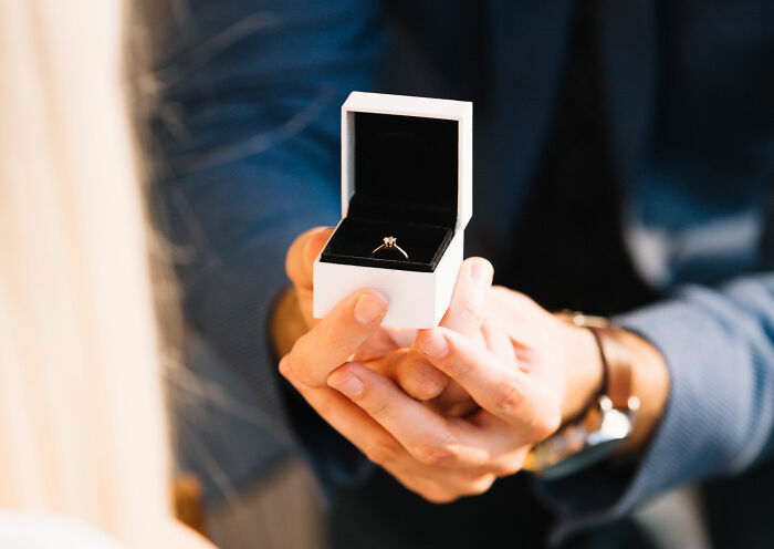 Person holding an open ring box indoors, related to people sharing wildest ways found out cheating stories.