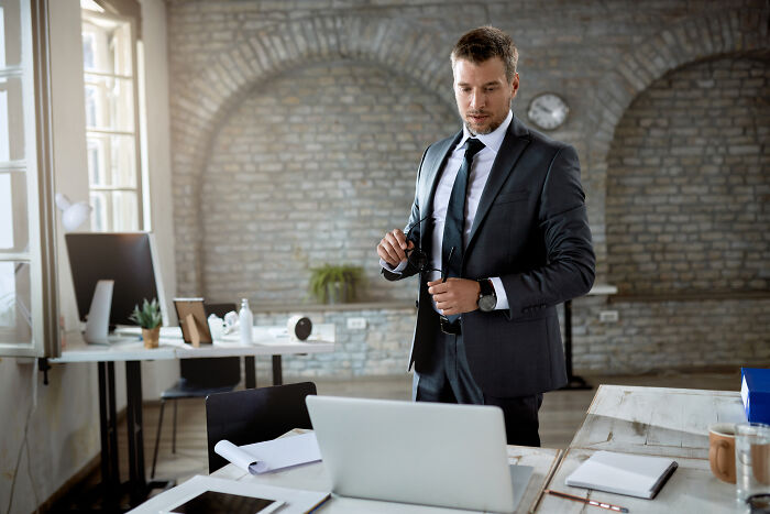 Businessman in a modern office setting reflecting on stories about the worst person they have ever met.