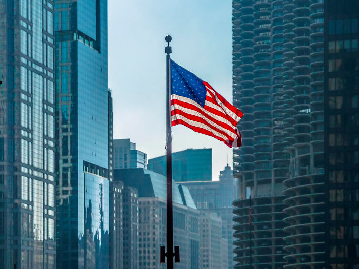 American flag waving amid skyscrapers, Moments People Faced scene of urban skyline and haze