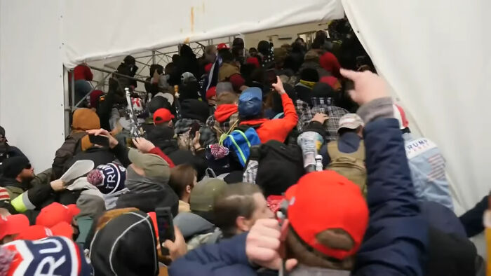 Crowd pushing into a tent entrance, many in red caps and winter coats, Moments People Faced a chaotic surge