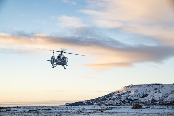 Helicopter flying over snowy plain and mountain at sunrise, capturing one of the moments people faced that felt unbelievable