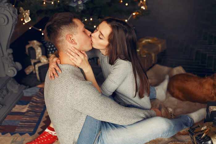 Moments people faced: couple kissing by Christmas tree, cozy room with gifts and a sleeping dog