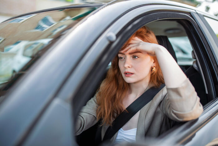 Young woman in a car looking out the window, reflecting on strange tales of folks who morphed unexpectedly.