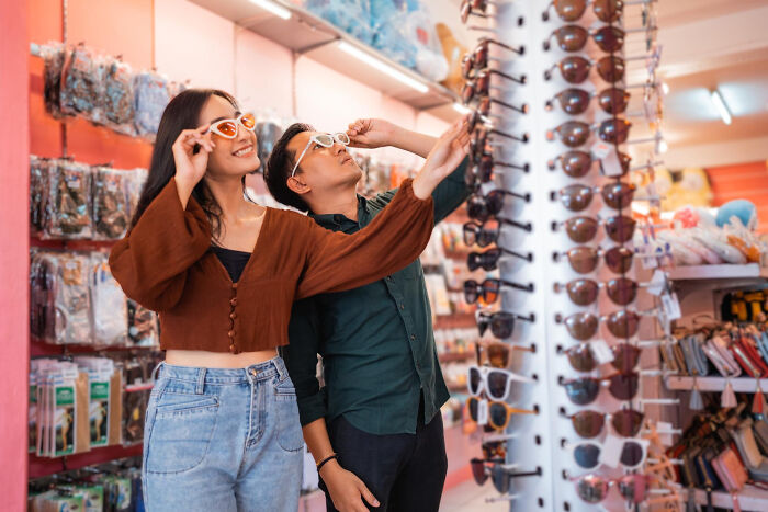 Two shoppers trying on sunglasses in a store, illustrating strange tales of folks who morphed unexpectedly.