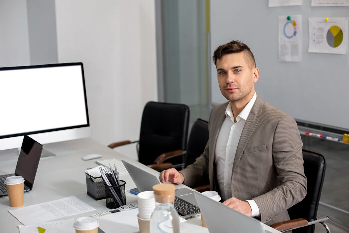 Young businessman working on a laptop in a modern office, illustrating strange tales of folks who morphed unexpectedly.