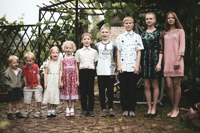 A large group of children standing outdoors under a garden archway, representing family secrets and dynamics.
