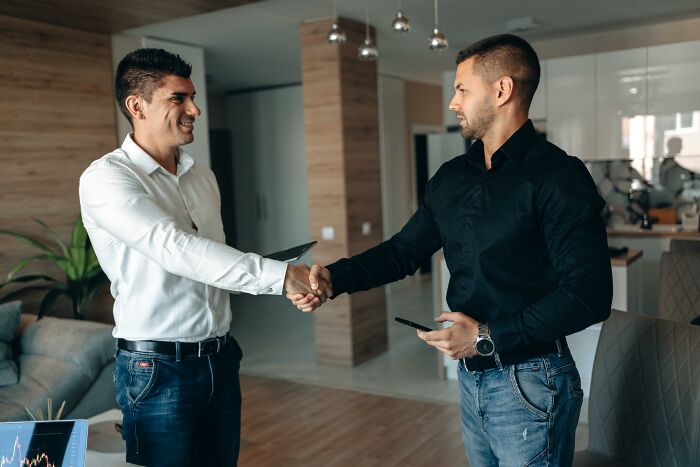 Two men shaking hands in a modern office, sharing cheat codes to make everyday life easier and more efficient.