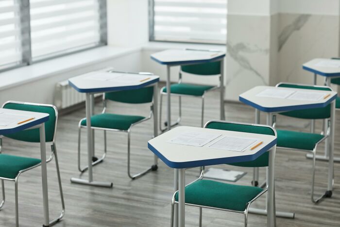 Empty classroom desks with pencils and test papers set up for a hard ACT exam practice session.
