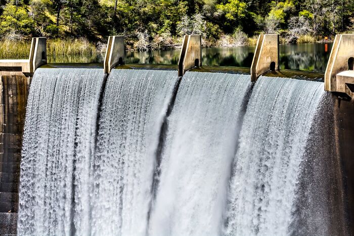 Hydroelectric dam with cascading water surrounded by trees representing progress and hope in America.