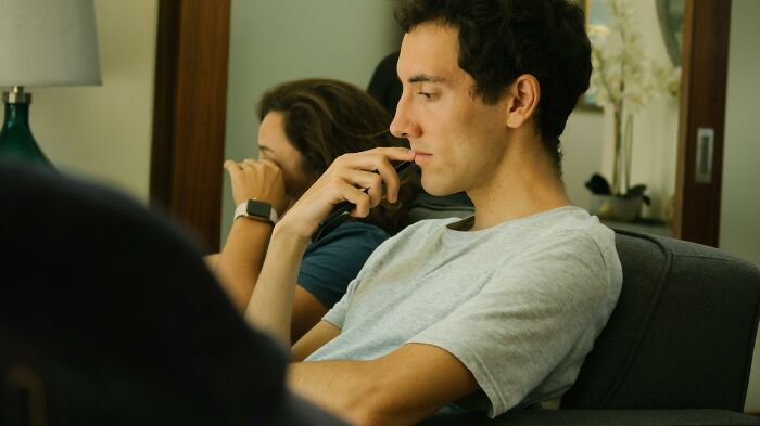 Young man deep in thought with a woman in the background, illustrating habits neurodivergent people thought were normal.