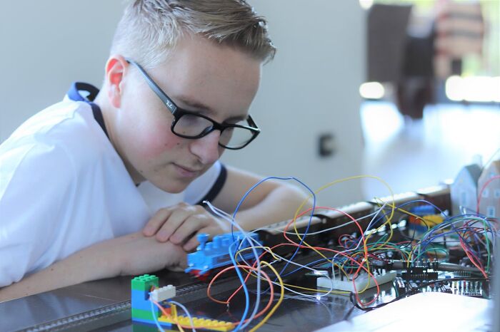 Young boy with glasses studying electronics and toy train, an example of creepiest displays of intelligence