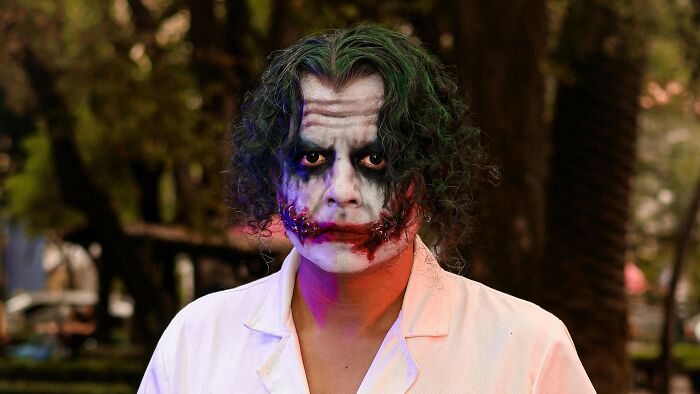 Movie character dressed as Joker with makeup and white coat, representing popular films in Reddit AITA descriptions.
