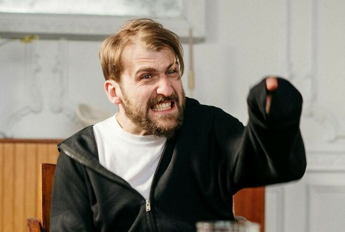 Angry bearded man in black hoodie shouting and pointing, evoking hospital workers and haunting last words