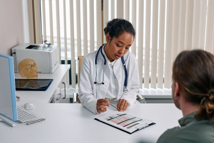 Doctor reviewing medical charts with patient in clinic, illustrating unexplainable medical events and prognosis surprises.