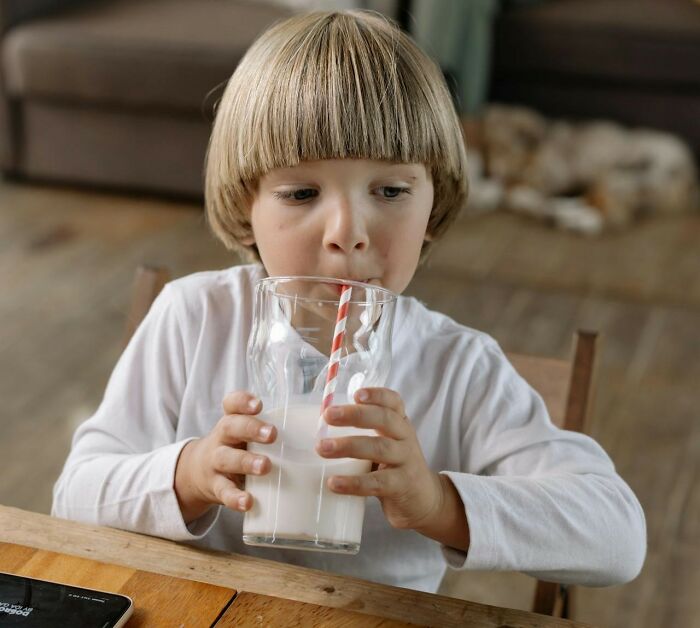 Young child drinking milk at a wooden table, illustrating moments that surprised people with intelligence.