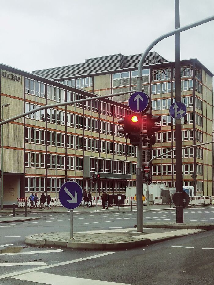 Urban intersection with red traffic light and arrow signs in front of office building, creepiest displays of intelligence