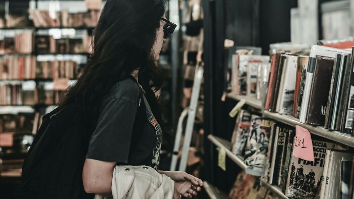 Young woman with long dark hair browsing books on shelves in a store focused on banned books and Harry Potter series.