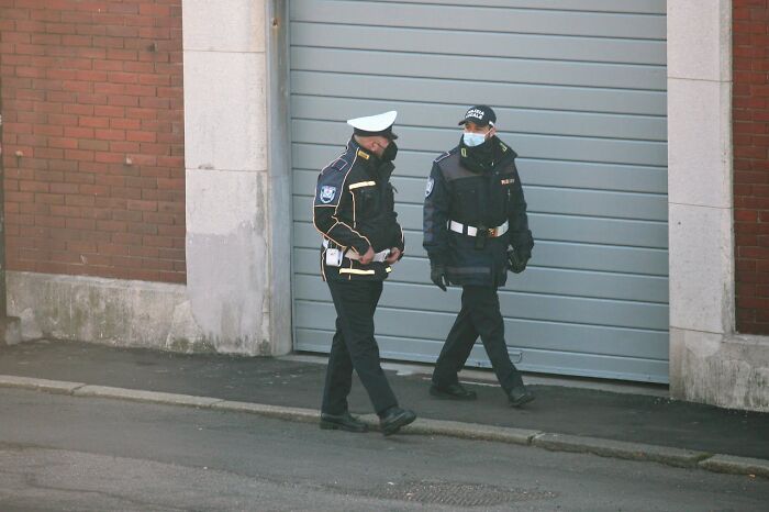 Two security guards walking outside a building during the night shift chaos at 3 AM on a quiet street.