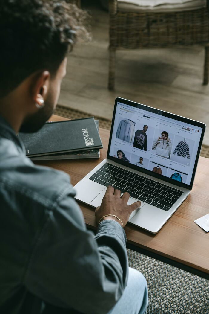 Man browsing online clothing store on laptop, representing things that shocked people after they got out of prison.