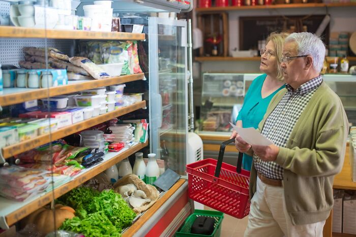 Two seniors with a shopping list looking surprised at groceries, illustrating shocks after getting out of prison.