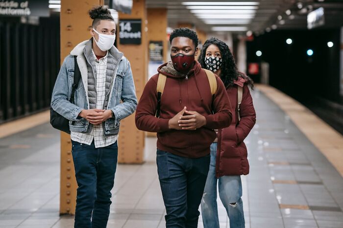 Three people wearing masks walking in a subway station, illustrating challenges people faced after they got out of prison.